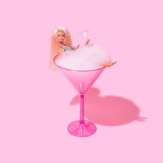 a barbie doll sitting on top of a pink cocktail glass