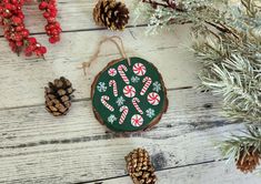 a christmas ornament with candy canes and snowflakes on it next to pine cones