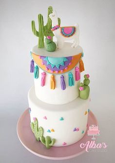 a three tiered cake decorated with cactus and tassels is on a plate