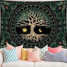 a couch with pillows and a tapestry hanging on it's wall, decorated with an image of a tree