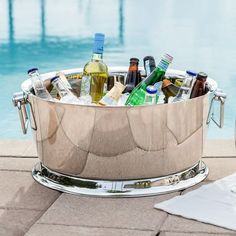 a metal bucket filled with bottles next to a swimming pool