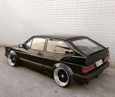 a black car parked in front of a white wall