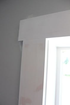 the corner of a room with white paint on it and a window frame in front