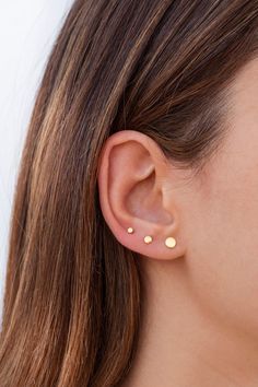 a close up of a woman's ear with two small gold dots on it