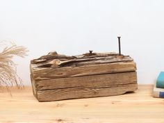 an old wooden box sitting on top of a table next to books and a plant