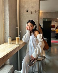 a woman sitting at a table with headphones on and looking off to the side