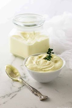 a white bowl filled with cream next to two spoons on a marble counter top