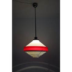 a red, white and black light hanging from a ceiling fixture in a dark room