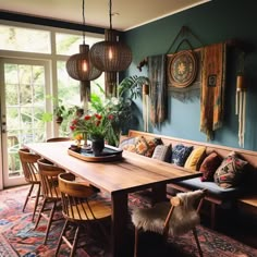 a dining room table surrounded by wooden chairs and hanging plants on the wall above it