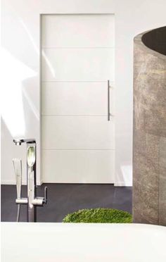 a bathroom with a large round sink next to a white door and green grass on the floor