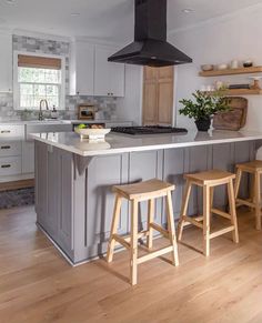 a kitchen with two stools and an island in the middle, surrounded by white cabinets