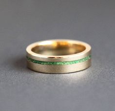 a close up of a wedding ring on a gray surface with green and yellow stripes