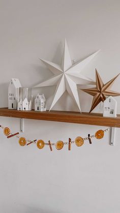 a shelf with some paper houses and a star hanging on it's side,