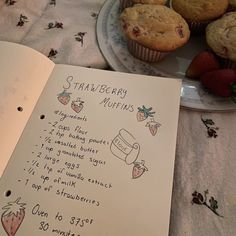 a recipe book with strawberries and muffins next to it on a table