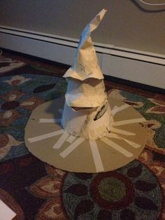 a white paper hat sitting on top of a wooden table next to a carpeted floor