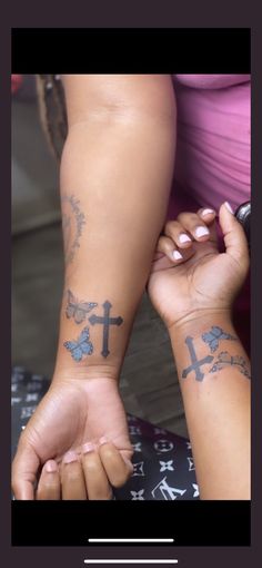 two people with tattoos on their arms holding each other's hands and one has a cross