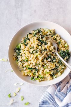 a white bowl filled with rice and vegetables on top of a blue and white towel