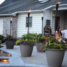 a man and woman sitting in front of a house next to some potted plants