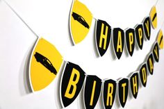 a happy birthday banner with yellow and black letters on it's sides, hanging from the wall