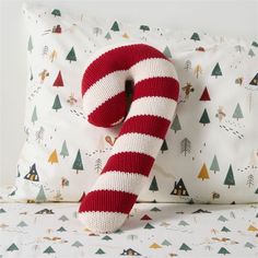 a red and white striped knitted pillow sitting on top of a bed