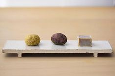 three different types of food sitting on a white platter with two pieces of bread and one piece of cake