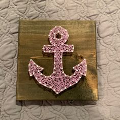 a string art anchor on a wooden plaque