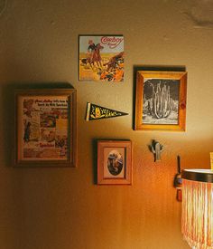 a wall with pictures and posters on it next to a light fixture in the corner