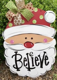 a wooden sign that says believe with a santa clause hat on it's head