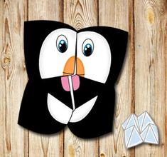 a black and white penguin with its mouth open next to an origami bird