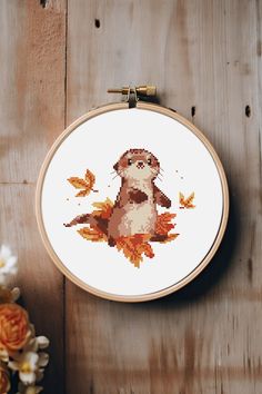 a cross - stitch pattern with an otter on it's back and leaves in the foreground