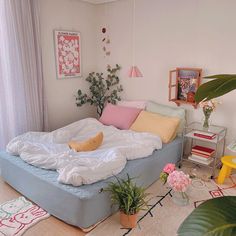 an unmade bed sitting on top of a wooden floor next to a potted plant