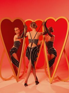 two women in black and white dresses standing next to each other with heart shaped mirrors behind them