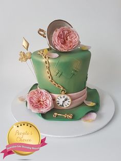 a green cake with pink flowers on top and a gold chain around the edge that says people's choice