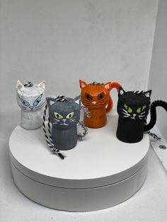 four different colored cats sitting on top of a white box with black and orange eyes