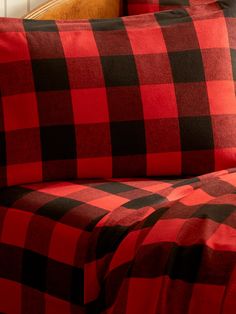 a red and black checkered comforter set on a bed with two pillow cases