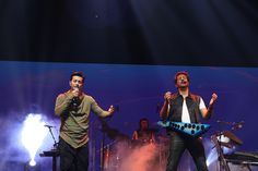 two men on stage singing into microphones