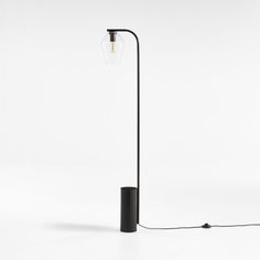 a black floor lamp with a clear glass shade on the top and an electric cord attached to it