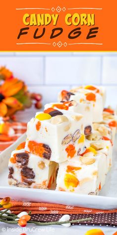 candy corn fudge on a white plate with orange and yellow flowers in the background