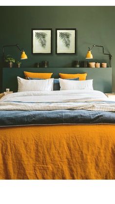 a bed with yellow and white pillows in a bedroom next to two framed pictures on the wall