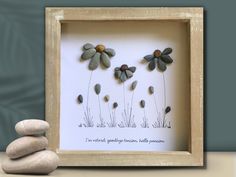 some rocks are stacked on top of each other in front of a picture frame with flowers