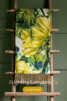 a yellow flowered towel hanging on a wooden ladder with the words, the lighting company shop now