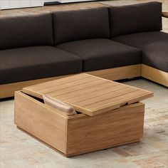 a wooden table sitting on top of a floor next to a couch and coffee table