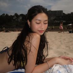 a young woman laying on top of a sandy beach