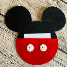 a close up of a mickey mouse head on a wooden surface with two white buttons