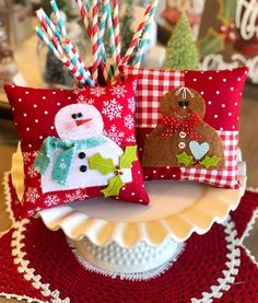 two decorative christmas pillows on a plate with straws in the shape of a snowman and a teddy bear