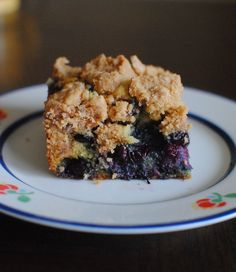 a piece of blueberry crumbler cake on a white and blue flowered plate