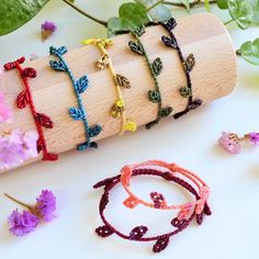 the bracelets are decorated with tiny flowers and leaves on wooden sticks, along with other jewelry items