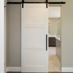 an open white door leading to a bathroom in a house with beige walls and flooring