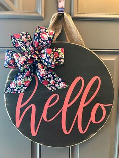 a door hanger that says hello on it with a bow hanging from the front