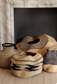 three woven baskets sitting on top of a wooden floor next to a fireplace mantel